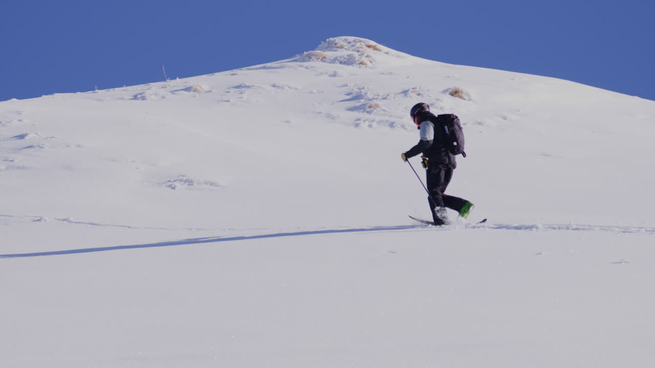 Freeride skier skinning up with Dents du Midi backdrop, then charging steep powder on a bluebird day near Champéry and Avoriaz.