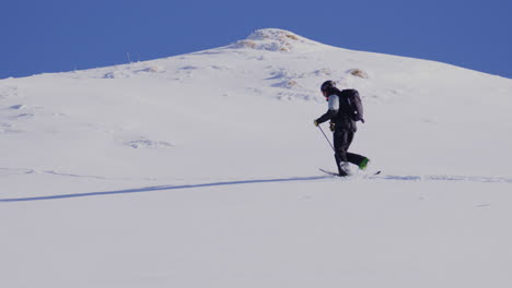 freeride skier skinning up with dents du midi backdrop, then charging steep powder on a bluebird day near champéry and avoriaz.