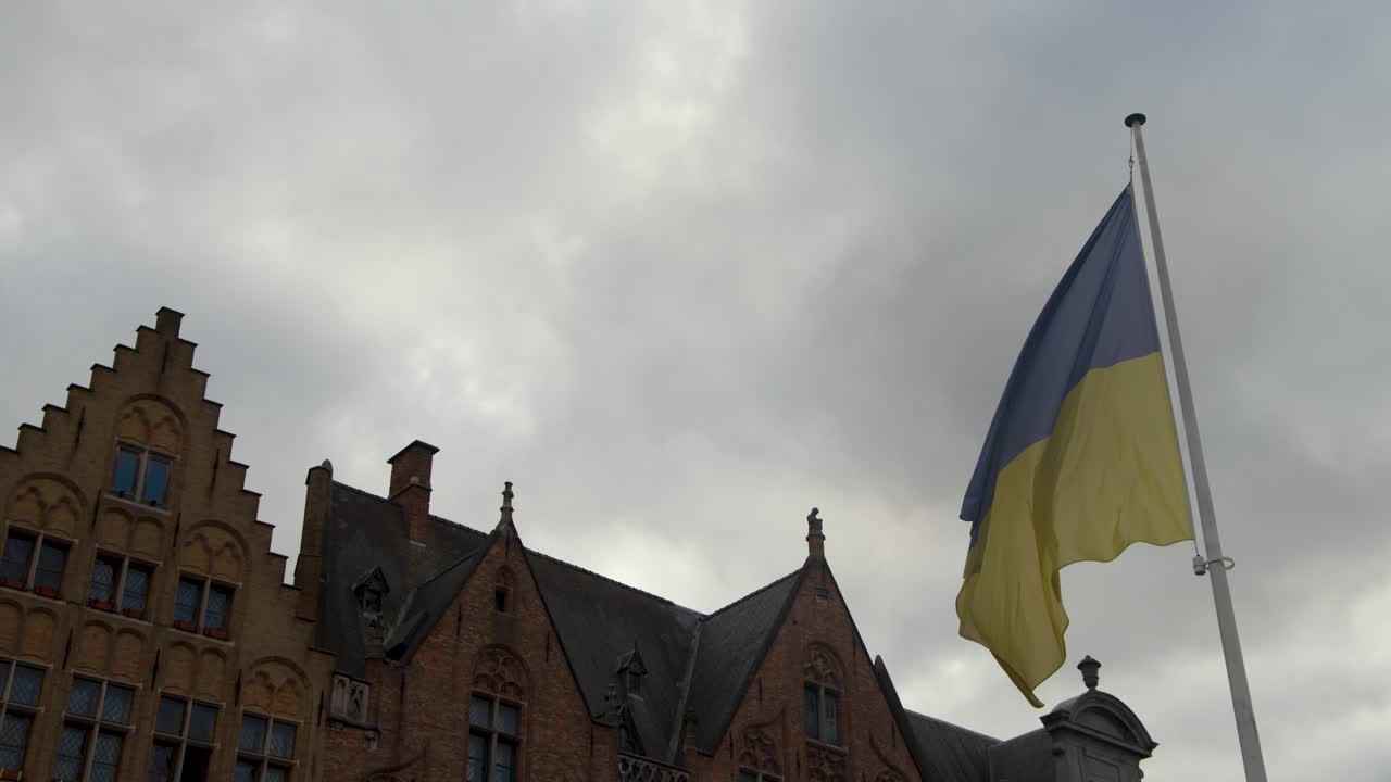 Ukraińska flaga powiewa na wietrze nad gotycką architekturą, pochmurne niebo, statyczna kamera, dzień