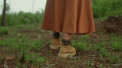 mujer con una falda larga y botas de senderismo caminando por un camino del bosque