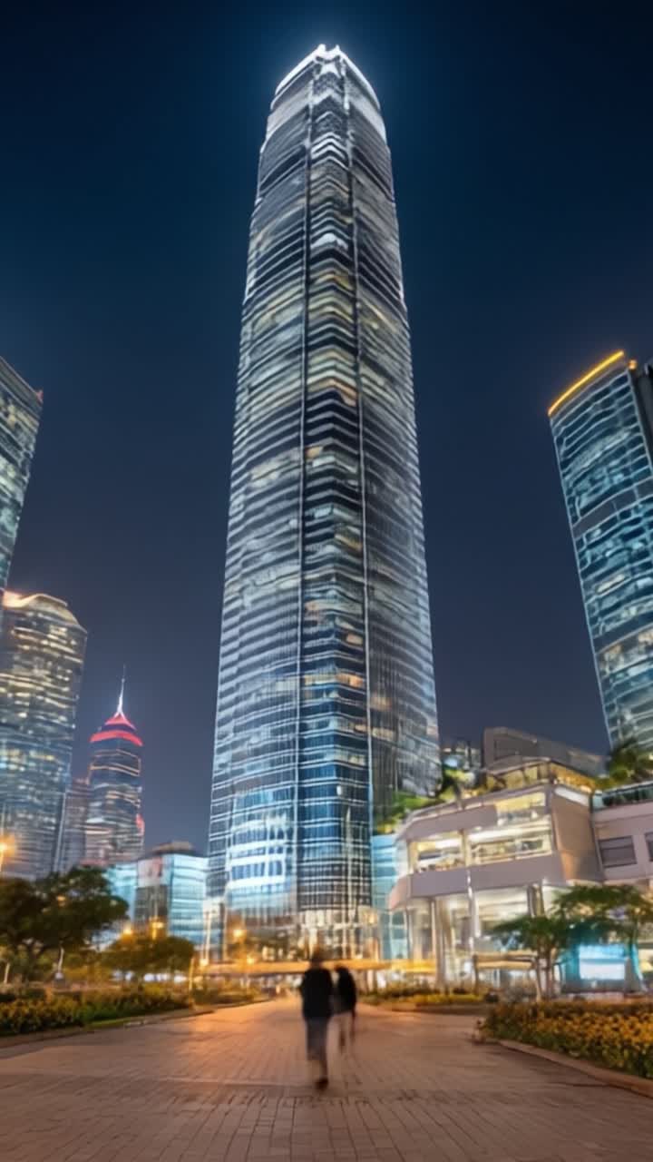 Um Arranha-céu Majestoso Iluminado à Noite: Esta imagem captura a arquitetura deslumbrante de um edifício de vidro imponente cercado por uma paisagem urbana, exibindo sua grandeza e luminosidade.