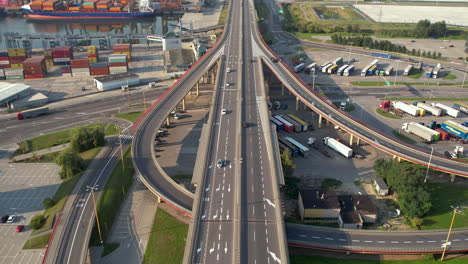 Luftaufnahme-Von-Autos,-Die-Auf-Der-Autobahn-In-Der-Nähe-Des-Hafens-Von-Gdynia-Fahren,-Mit-Andockenden-Containerschiffen,-Polen