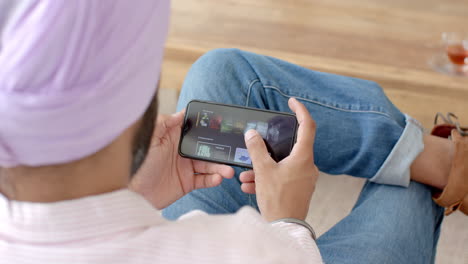 watching videos on smartphone, man relaxing at home in casual attire