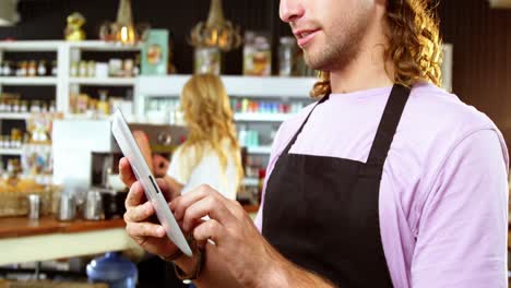 Waiter-using-digital-tablet-at-counter