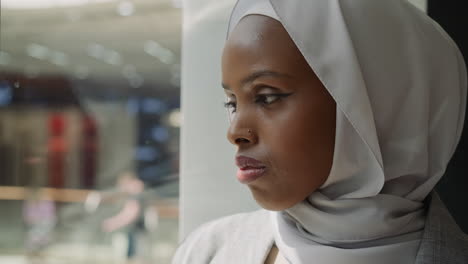 african-american woman adjusts hijab in shopping mall