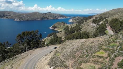 flyover: car rounds corner on highway beside lake titicaca, bolivia