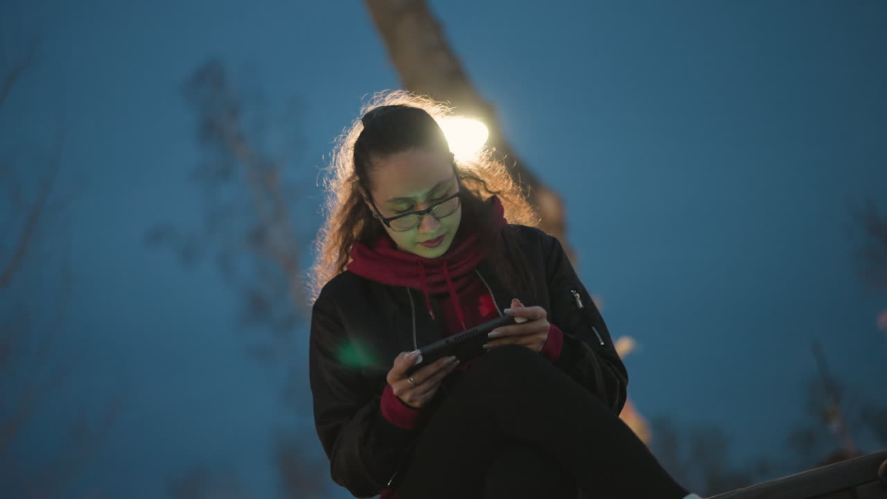 Live Streaming Beneath Streetlamp With Cinematic Glow Effect And Audience Engagement, Asian Life Broadcaster Under Glow Of Lamp Halo With Cinematic Tones And Mobile Viewer Interaction