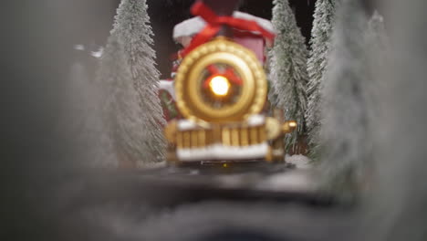 vintage toy locomotive riding through snowy forest and snowfall