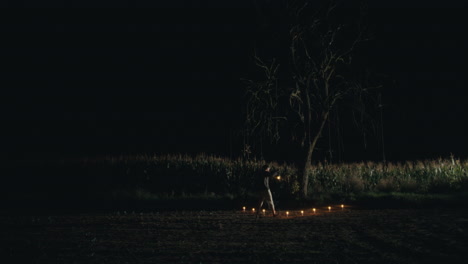 person with lantern and candles in a mysterious night field