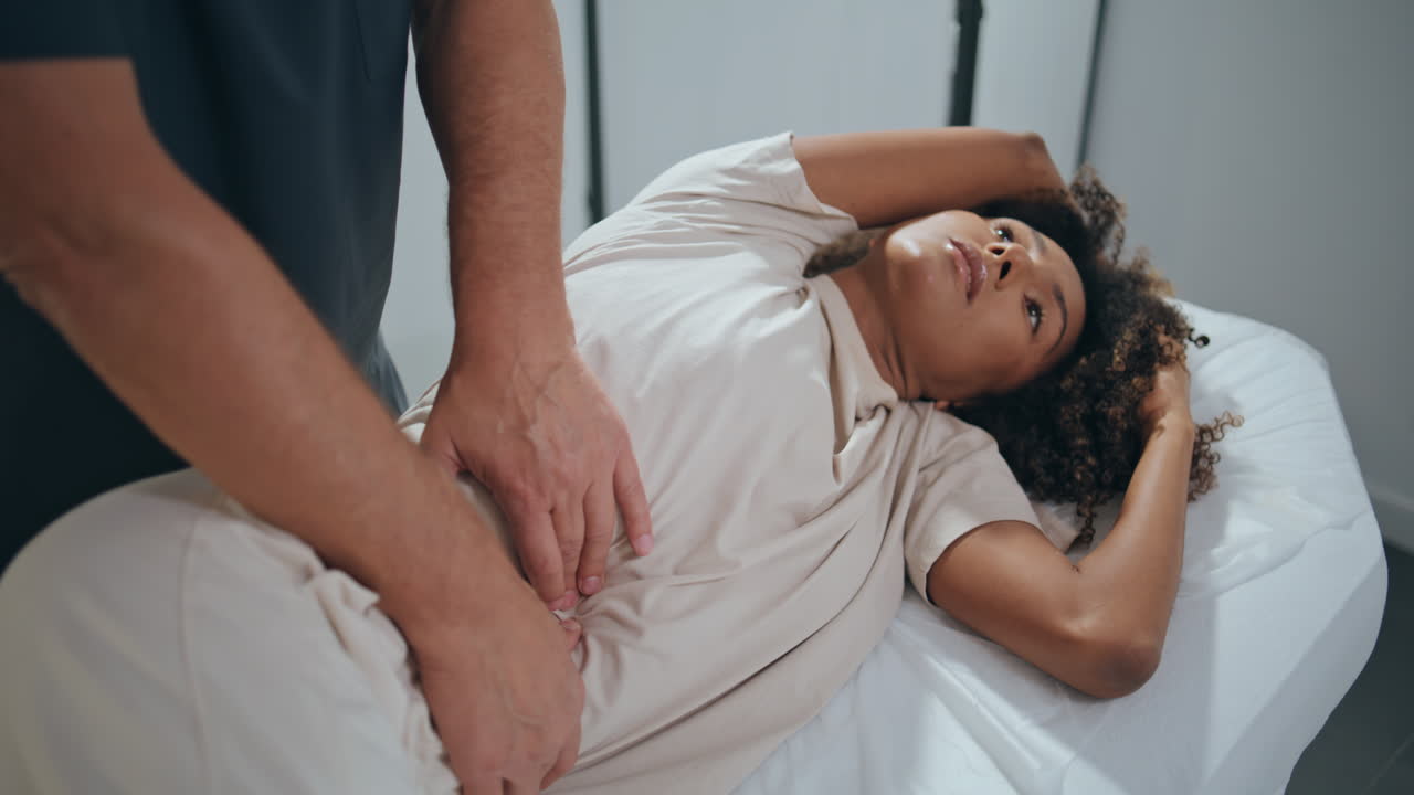 Chiropractor examine patient stomach in clinic. Client lying couch