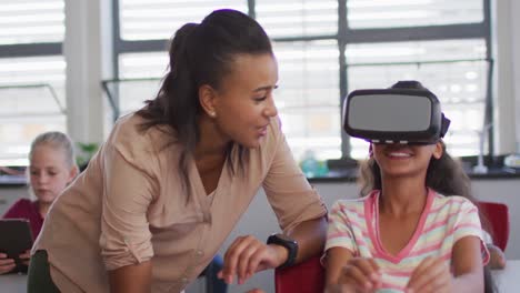diverse female teacher standing near happy schoolgirl wearing virtual reality glasses