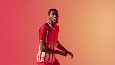 african american male soccer player kicking football over neon pink lighting
