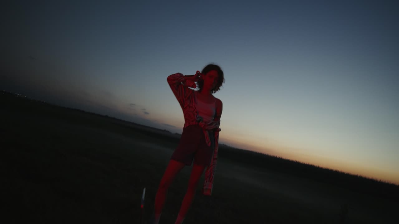 mujer en el campo al atardecer, iluminada por una luz roja