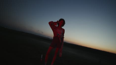 woman in field at sunset, illuminated by red light