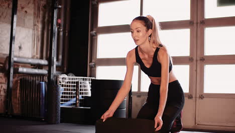 Cámara-Lenta-De-Mujer-Atlética-Poniendo-Colchoneta-De-Ejercicios-En-El-Piso-En-El-Gimnasio