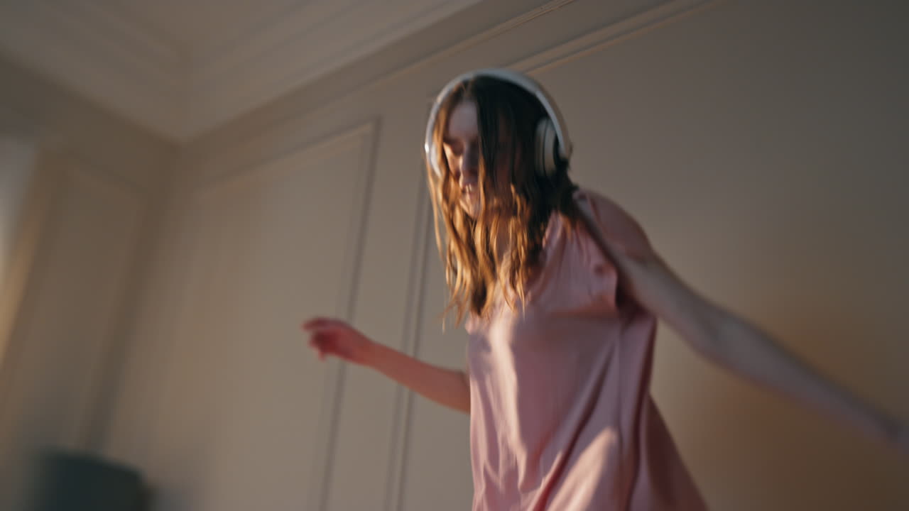Slim legs jumping bedroom in sunlight closeup. Energetic joyful woman listening