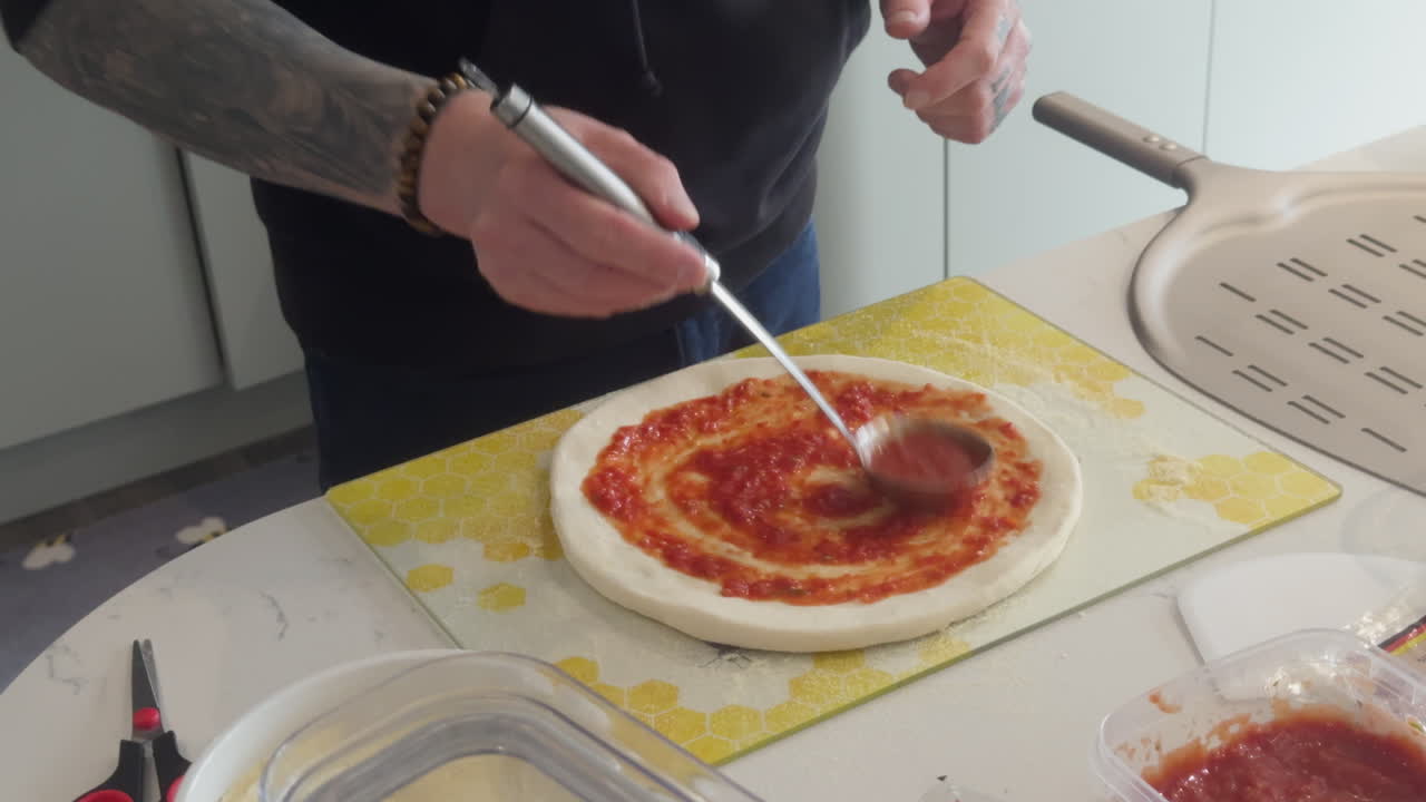 Creating a perfect pizza from scratch in a cosy kitchen while preparing the fresh sauce and spreading it on the dough.