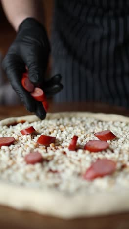 chef preparing pizza with sausage and cheese toppings