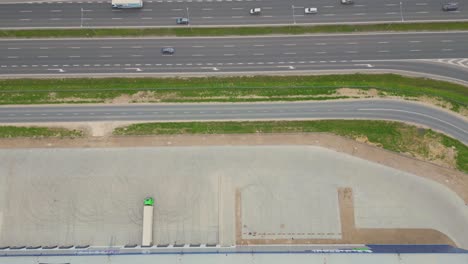 Logistics-park-with-warehouse,-loading-hub-and-many-semi-trucks-with-cargo-trailers-standing-at-the-ramps-for-load-unload-goods-at-sunset