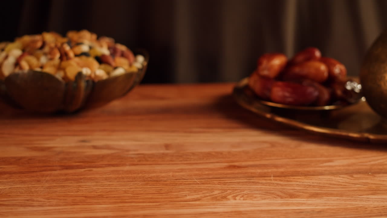 Hands holding baklava on a gold tray with dates and nuts