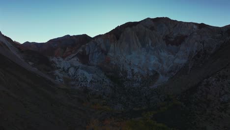convict lake canyon trail rugged mountainside layers mammoth lakes drone aerial california autumn fall evening sunset shaded valley peaks clear skies yellow birch aspen trees backwards motion