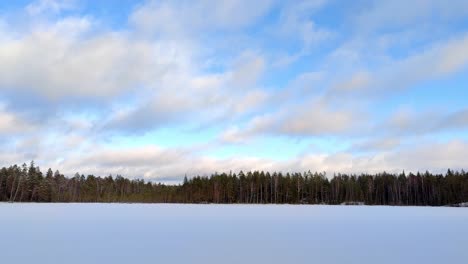 frozen lake in snow under blue cloudy sky