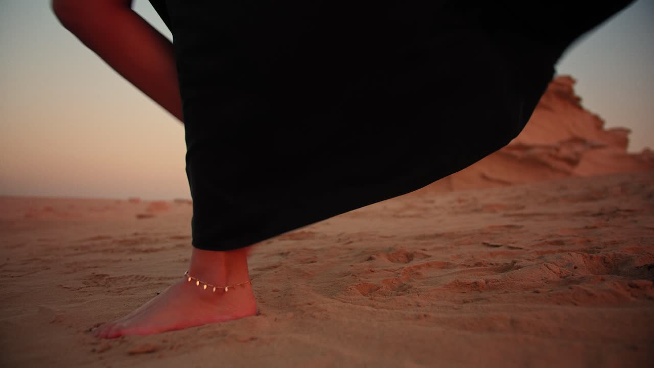 Ragazza che cammina a piedi nudi nel deserto indossando una cavigliera, tra le dune fossili degli Emirati Arabi Uniti, Abu Dhabi, Dubai.