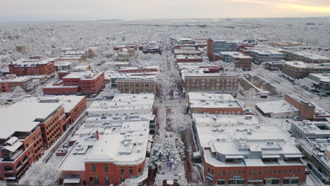 low drone shot moving forward of boulder colorado and downtown pearl street after large winter snow storm covers trees, homes, streets, and neighborhood in fresh white snow