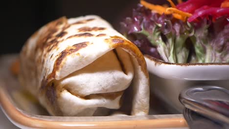 close-up of a delicious wrap with side salad, being eaten