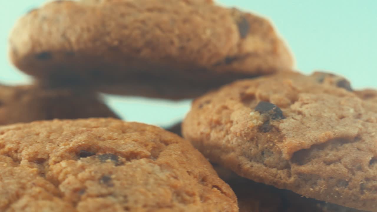 A macro shot of a white plate full of tasty chocolate chip cookies, on a 360 rotating stand, studio lighting, slow motion, 4K video