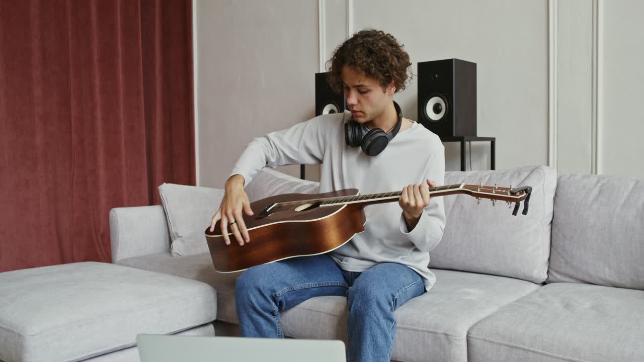 joven tocando la guitarra acústica en casa