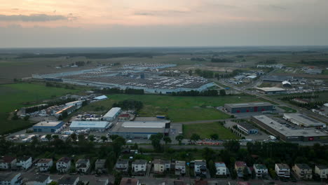 aerial view of an industrial area in lubawa, poland, showing large warehouses and factories surrounded by fields at sunset, highlighting the scale of industrial development