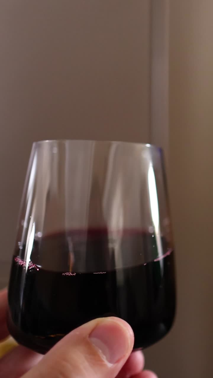 Persona che sorseggia vino durante un volo, con intrattenimento di bordo visibile