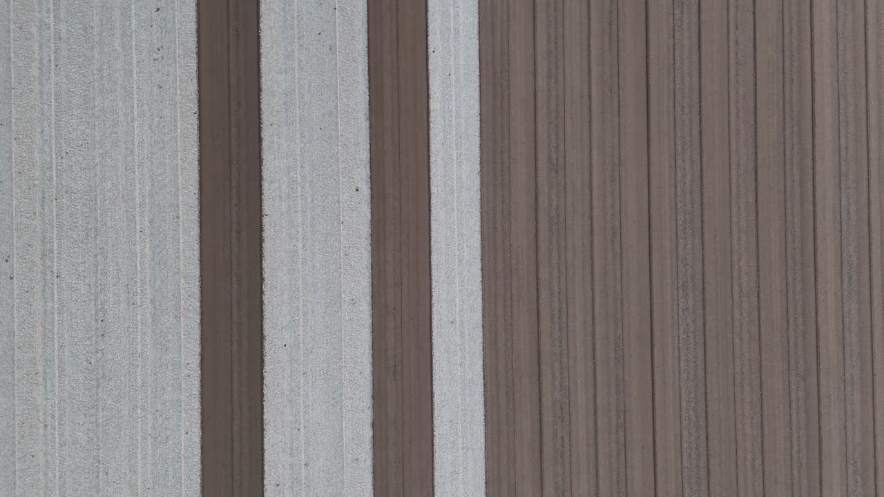 Tracking drone shot of a tractor smoothing freshly plowed soil in a large agricultural field, highlighting mechanized land preparation and precision farming