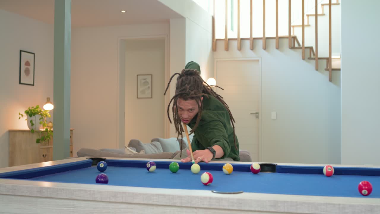 Man entering at home with pool cue aiming and striking shot on pool table for fun