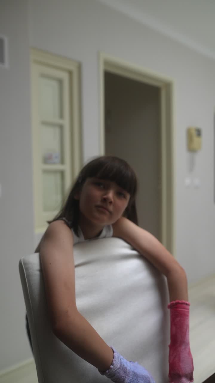 Ragazza con il braccio infortunato che riposa su una sedia