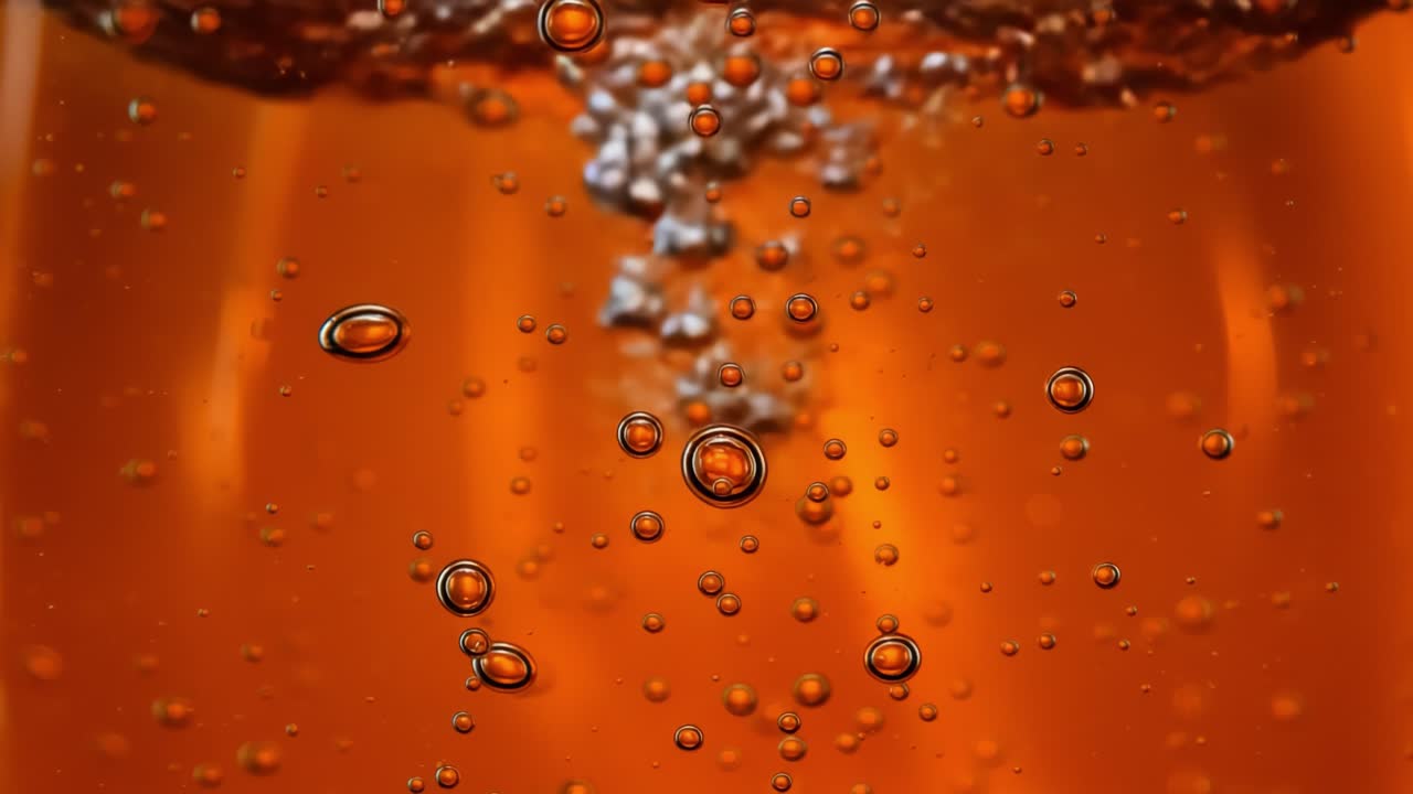 Captivating Close-up of Bubbles Rising in a Sparkling Orange Liquid, Showcasing the Dance of Effervescence and Light Reflection