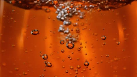 captivating close-up of bubbles rising in a sparkling orange liquid, showcasing the dance of effervescence and light reflection