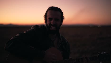 man playing guitar at sunset