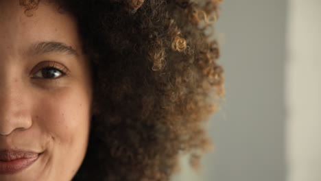 curly-haired woman gazing thoughtfully, close-up on eye and hair texture, at home, copy space