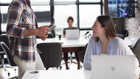 young caucasian woman and asian man collaborate with a tablet in a business office setting