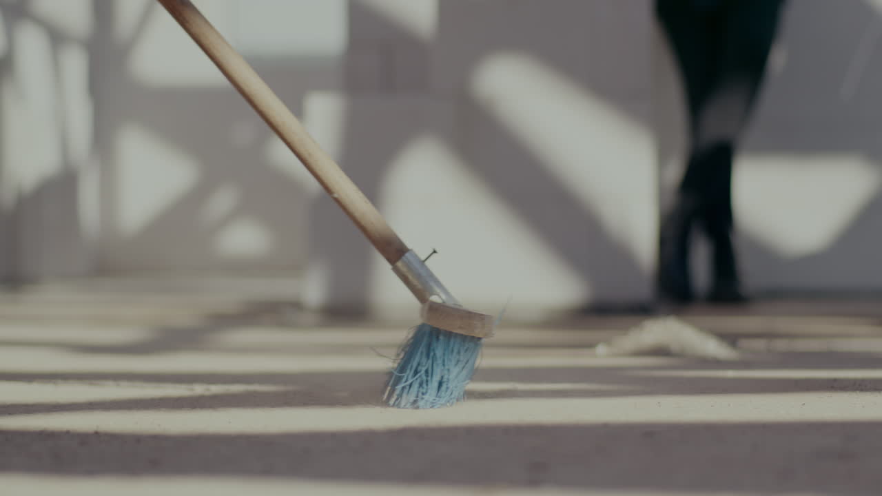 Lockdown shot of broom blowing dust from ground at construction site