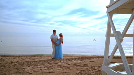 expecting parents on beach. pregnant couple touching belly with love and care