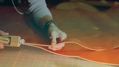 animation of caucasian female worker cutting leather in workshop