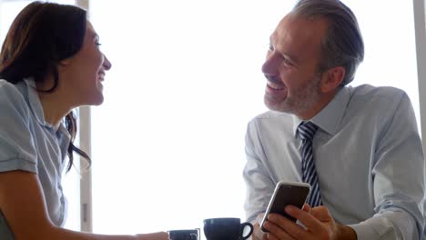 Woman-and-businessman-interacting-with-each-other-while-using-mobile-phone