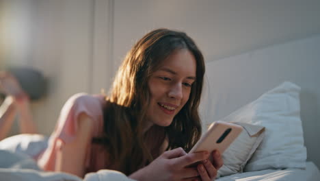 pretty girl browsing social media in bed closeup. happy young woman resting home