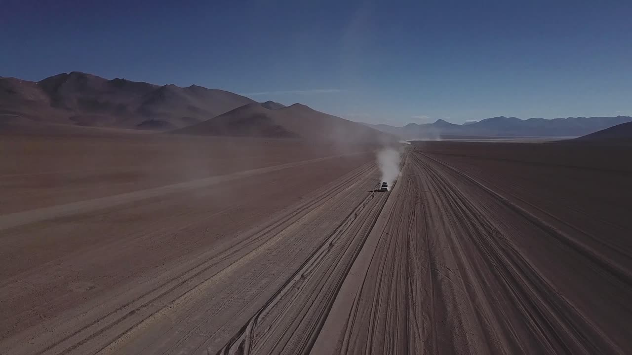 fotografía épica de un avión no tripulado de un coche conduciendo en una carretera de tierra desierta, la ruta de bolivia y chile