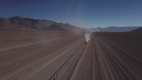 epic drone shot of a car driving on deserted dirt road, bolivia and chile route
