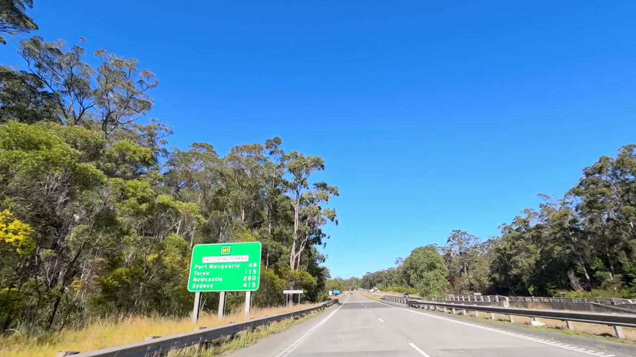 Dal punto di vista di un veicolo che guida lungo un'autostrada soleggiata attraverso la boscaglia australiana a South Kempsey