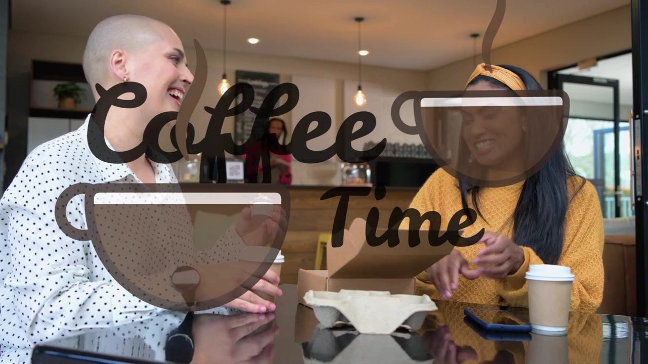 Dos mujeres sentadas en la mesa de un café, abriendo una caja de comida para llevar y mostrando el smartphone, compartiendo risas.